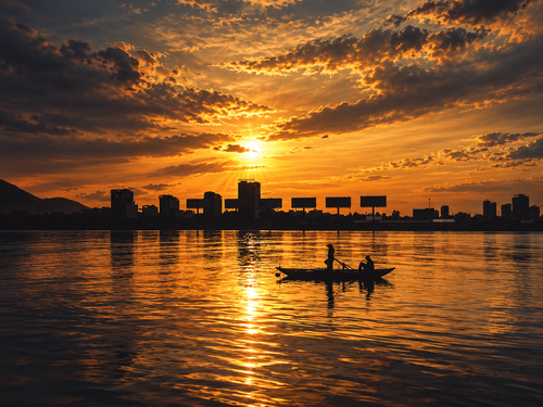Golden sunset over Han River Da Nang with wooden boat silhouette and city skyline reflection digital wall art print